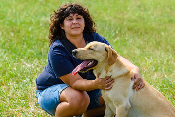 Young woman with cute labrador retriever dog at the meadow