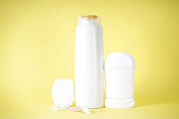 Shampoo bottle, deodorant and dental floss on a yellow background.