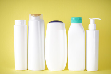 Plastic bottles for body care and cosmetics on a yellow background.