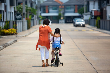 A portrait of a little Asian girl and her grandmother doing fun activities together at a happy home.