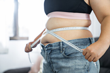 Chubby obese woman  check out body fat with measuring tape health care diet lifestyle concept