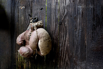 Old boxing gloves hang on nail on wooden wall as sport retirement concept.