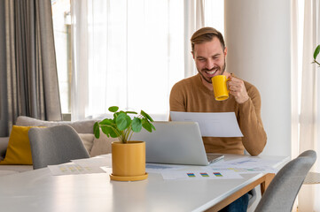 Young businessman drinking morning coffee while having online business meeting at home 