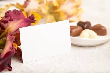 Foto op Plexiglas White business card with chocolate candies and iris flowers on gray concrete background. side view, copy space. © zgurski1980