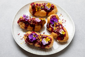 Small eclairs with bluberry icing and violet flowers