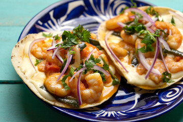Mexican food. Shrimp tacos with melted cheese and poblano pepper called gobernador on turquoise background.