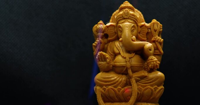 Ganesh Chaturthi Concept: Statue of the Hindu god Ganapati with a black background. Confetti Embellishments fell
