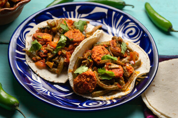 Mexican food. Chorizo and nopales tacos on turquoise background