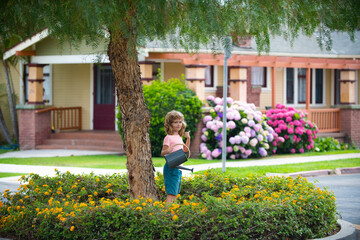 Boy pouring water on the trees. Kid helps to care for the plants with a watering can in the yard garden. © Volodymyr