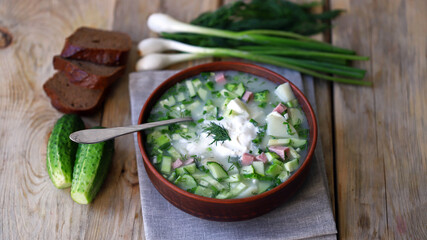 Cold summer soup okroshka with sausage, sour cream and herbs.