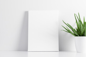 White canvas mockup with aloe vera plant in pot on table. Front view