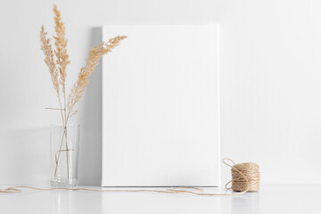 White canvas mockup with shadow and glass vase with reeds foliage branches on white table