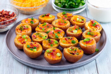 Mini red skinned loaded potatoes with crispy bacon, scallions and sharp cheddar cheese, horizontal
