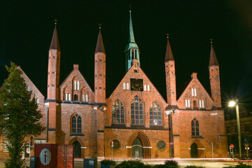 Fototapeta na wymiar Heiligen Geist Hospital (Holy Spirit Hospital) in Lubeck at night, one of the oldest existing social institutions in the world and a significant historic brick building landmark in the city