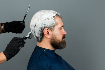 Bearded man color hair. Process of a man hair coloring at hairdresser salon.