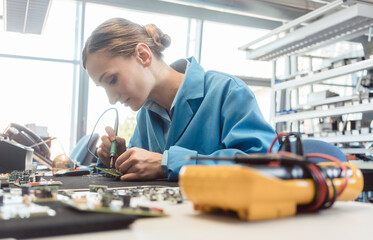 Worker in electronics manufacturing soldering a component for the prototype series by hand - 455171476