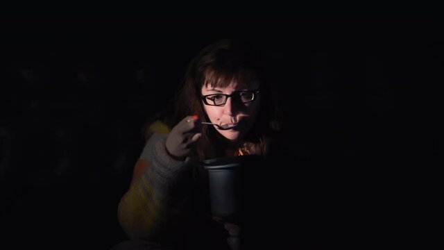 Serious Woman Sitting On The Bed In The Evening And Attentively Watching Tv, Brunette Woman Eating Ice Cream At Night And Watching Tv