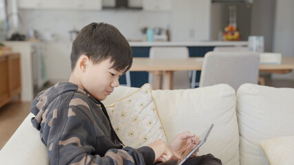Mixed Asian preteen teen boy making video calling with digital tablet at home, using zoom online virtual class , social distancing, homeschooling, remote learning, new normal concept
