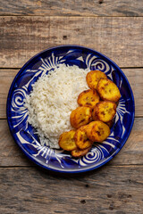 Rice and fried banana also called cuban style on wooden background