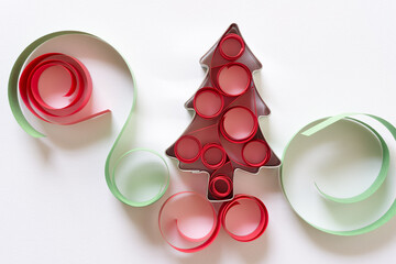 Christmas cookie cutter in the shape of a tree decorated with paper swirls on white