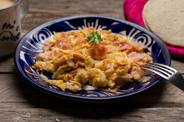 Scrambled eggs with ham for breakfast on wooden background