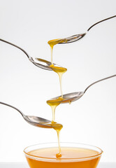 Fresh flower honey drips from a spoon into a spoon on a white background. Organic vitamin food.