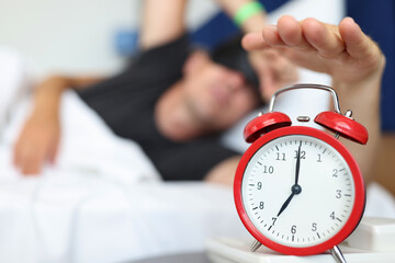 Rested man reaches for watch button to turn off daily alarm and wake up