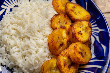 Rice and fried banana also called cuban style on wooden background