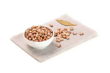 alubia pinta en bol  blanco sobre una servilleta de tela gris con hoja de laurel seco, imagen aislada recortada en fondo blanco