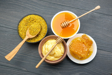 Fresh flower honey of different varieties, pollen and honeycomb with spoons on a wooden background....
