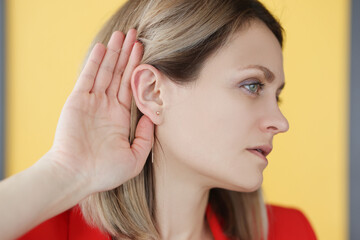 Deaf-mute woman holding her hand near ear