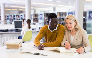 Obraz premium Friendly adult students preparing in library. High quality photo