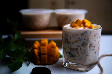Mango Milk Cheese with a half of mango on white table with packaging for sale as background