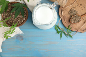 Obraz na płótnie Canvas Hemp milk, seeds and leaves on light blue wooden background, flat lay. Space for text