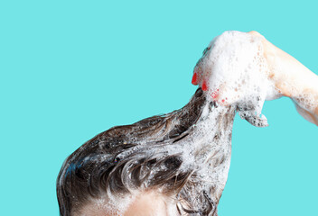 A girl washes her hair with shampoo on blue background.