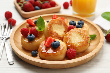 Delicious cottage cheese pancakes with fresh berries and honey on white wooden table