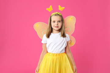 Cute little girl in fairy costume with yellow wings on pink background