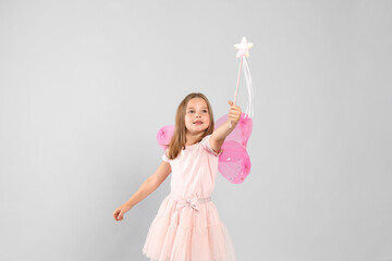 Cute little girl in fairy costume with pink wings and magic wand on light background - obrazy, fototapety, plakaty
