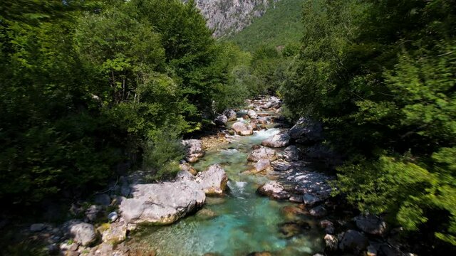 Mountain river with clean water streaming across cliffs and trees in valley of Valbone, Albania
