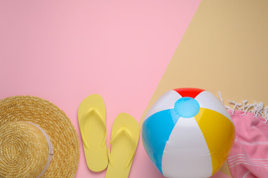 Colorful beach ball, hat, blanket and flip flops on color background, flat lay. Space for text