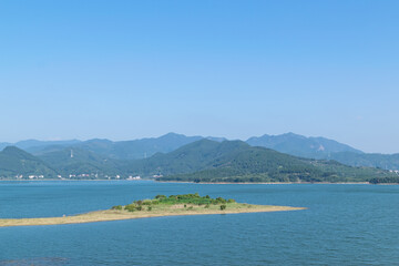 Blue sky, green mountains and trees surround the lake
