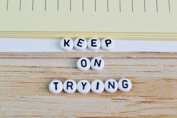 Notebook and alphabet beads with text KEEP ON TRYING