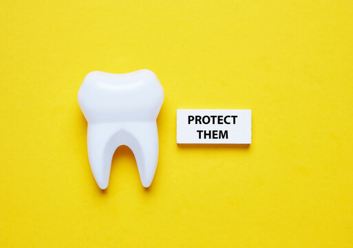 A picture of fake tooth and wooden block with the word protect them.