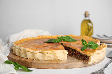 Delicious pie with minced meat on white wooden table