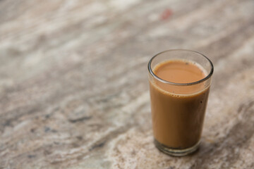 小さいグラスに入ったインド式ミルクティーのチャイ