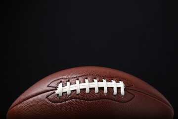 American football ball on black background, closeup. Space for text