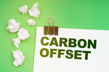 On a green background, crumpled paper and a sheet with the inscription -Carbon offset