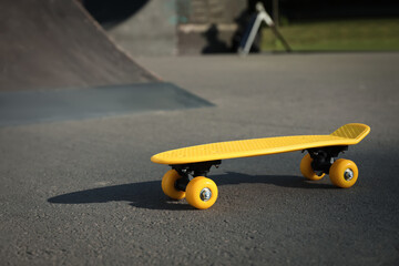 Modern yellow skateboard on asphalt road outdoors