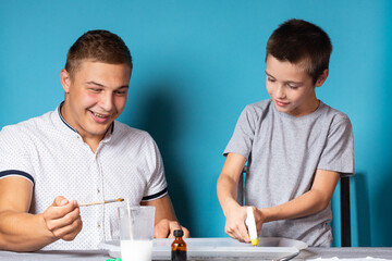 Dad and son are conducting chemical experiments, observing the change in color of a chameleon as a...