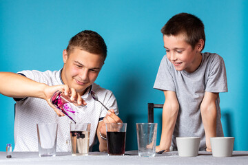 Chemistry education and training concept. Close-up of a boy and his dad, scientists pour potassium permanganate into a test tube for an experiment with a change of colors, experiments at home